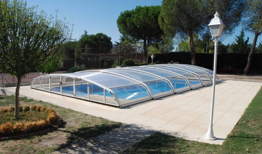 Portada del blog tipo de cubierta para tu piscina en la que se observa una piscina de urbanización con una cubierta retráctil